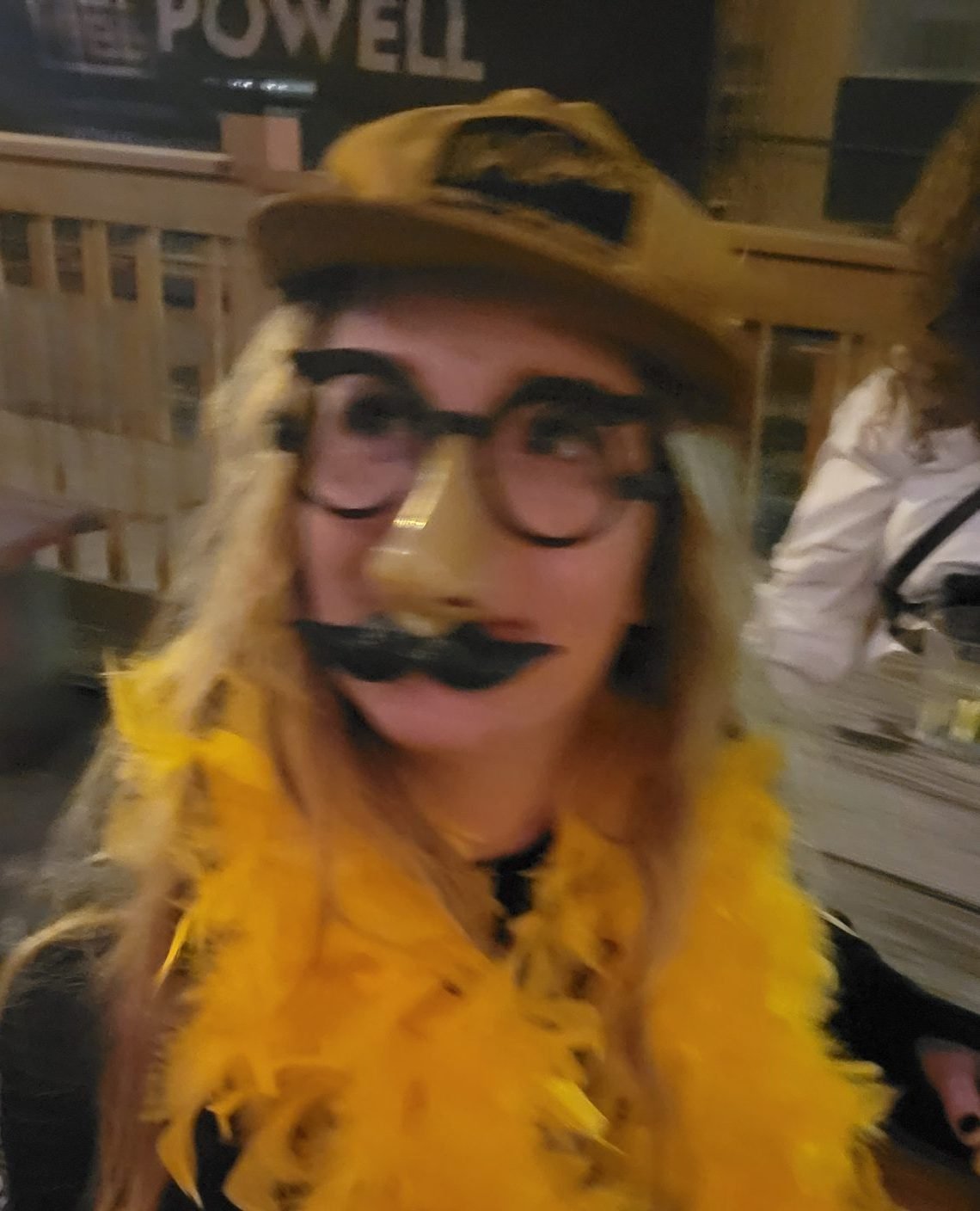 Bartender in mask serving drinks on Halloween night in a dimly lit bar, smiling under pressure