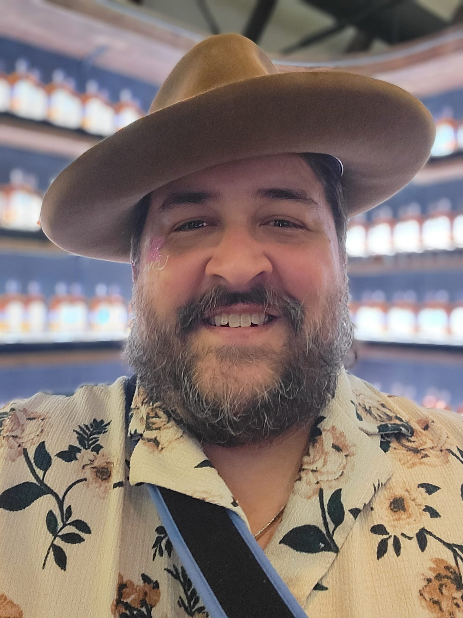 Chris Mallon smiling in a wide-brim hat and floral shirt, captured in a candid moment before leading a hospitality leadership session on Customer Service