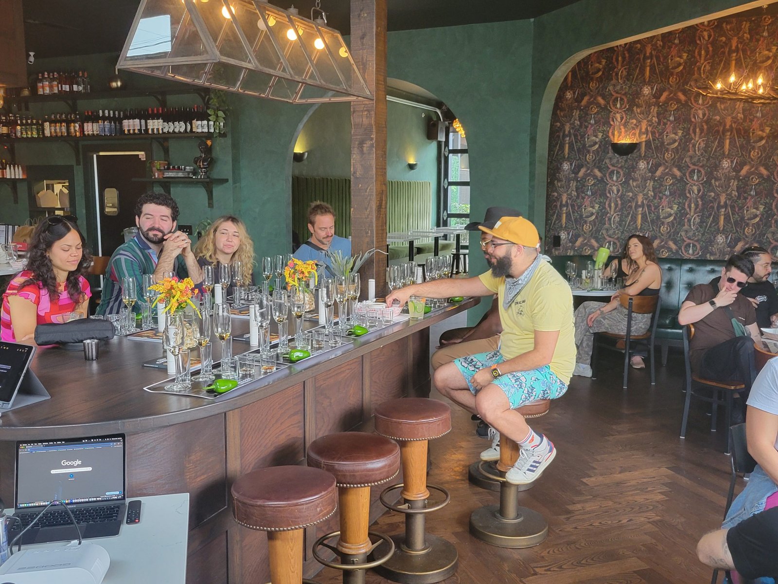 Hospitality Workshop Bar Session A hospitality workshop in session for the new year, with guests seated at a bar while an instructor leads a hands-on cocktail experience in a warmly lit space.